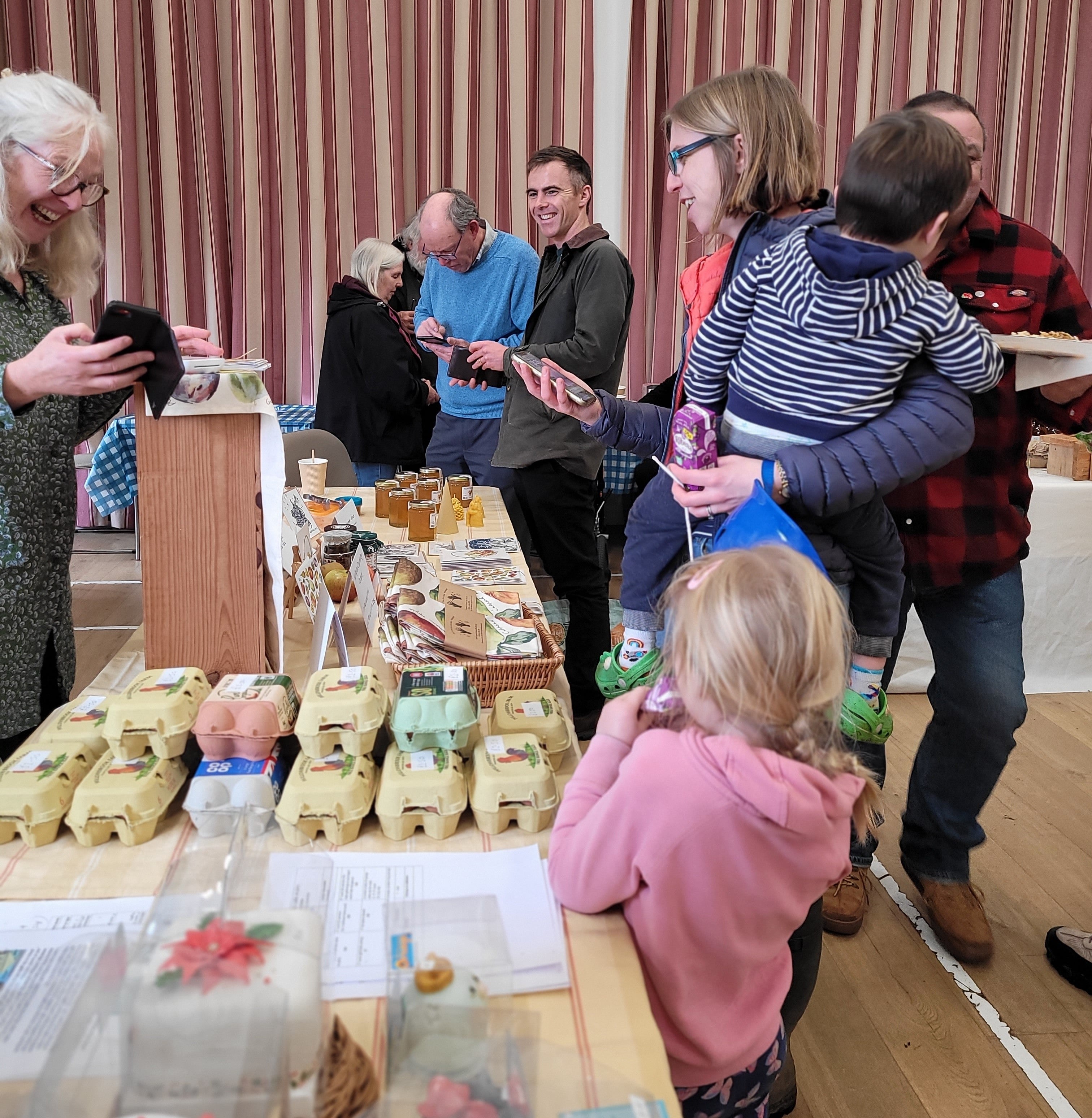 People gathered around a table with food items in a room with striped curtains.